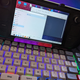 A Steam Deck sits on a dock in front of a keyboard and trackball mouse.